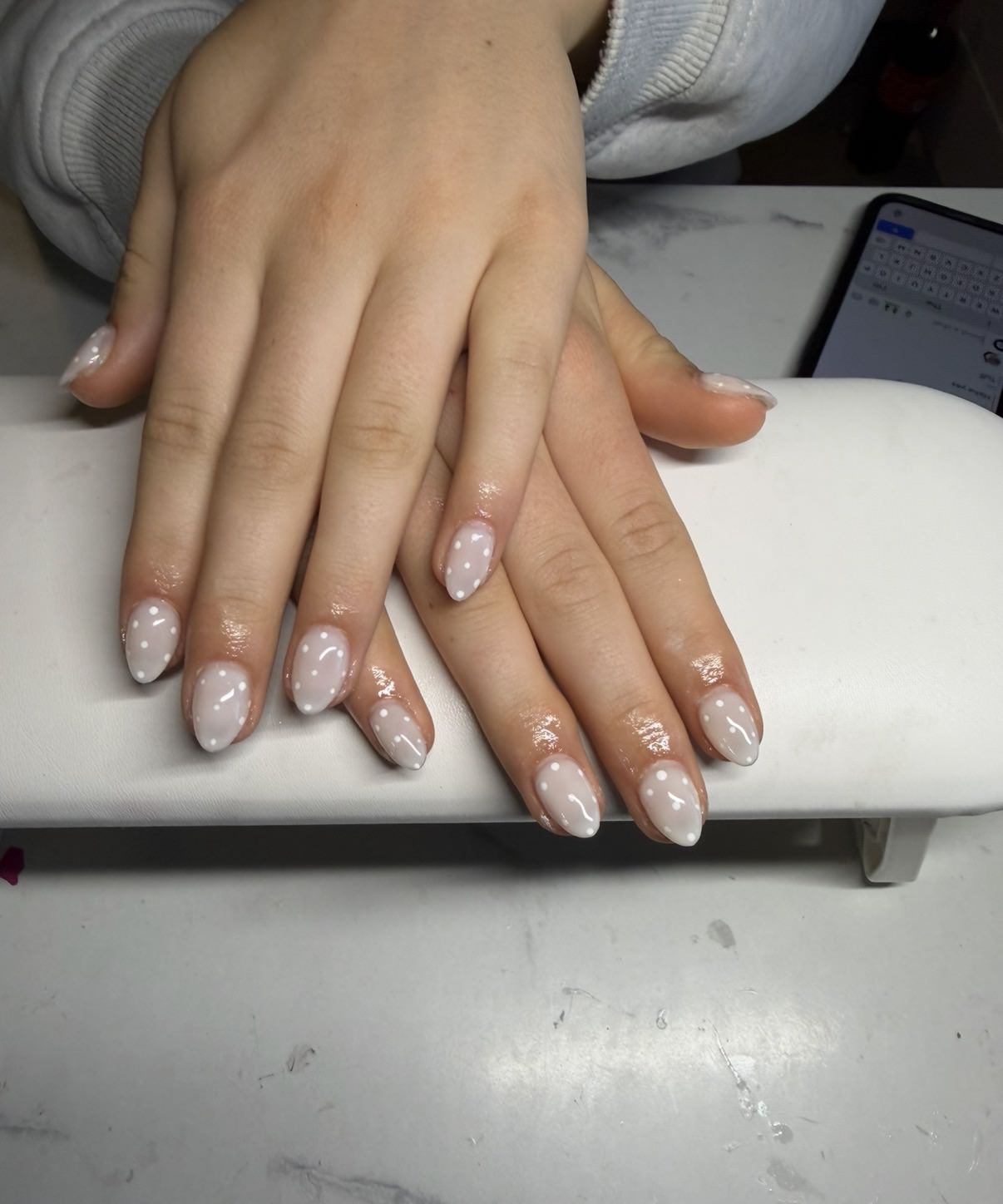 White dotted structured gel nails with a refined glossy finish by Raegan